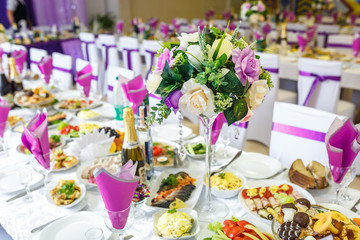 Beautiful flowers on elegant dinner table in wedding day. Decorations served on the festive table in violet background