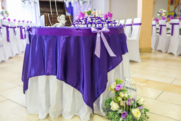 Beautiful flowers on elegant dinner table in wedding day. Decorations served on the festive table in violet background