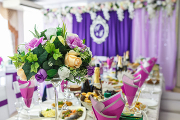 Beautiful flowers on elegant dinner table in wedding day. Decorations served on the festive table in violet background