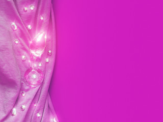 The glass sex toy (butt plug) is on a fuchsia fabric. Rhinestones are located nearby.