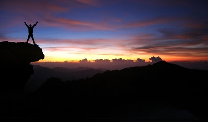 silhouette of man on top of mountain at sunset