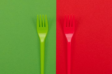 Pair of plastic forks in red and green atop of background