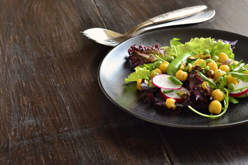 Healthy vegetarian bowl salad with chickpeas, green peas, radish and pistachios, copy space