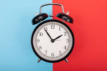 black metal arrow alarm clock on blue-red background