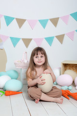 Easter Beautiful little girl on a white background with Easter colorful eggs, Easter basket and hares. Easter location, decorations. Family holidays, traditions. Colorful room. Child development. 