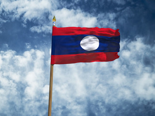 Laos flag Silk waving flag of Laos made transparent fabric with wooden flagpole gold spear on background sunny blue sky white smoke clouds real retro photo Countries of world 3d illustration