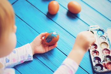 Naklejka premium Little girl painting Easter eggs. Hands doing Easter eggs. preparing for Easter