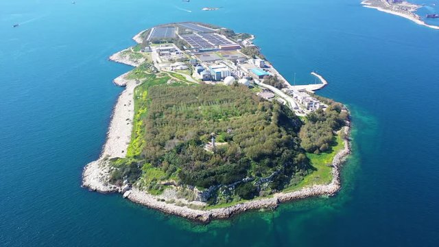 Aerial drone bird's eye video from island of Psitaleia the largest sewage treatment plant in Europe, Saronic gulf, Peiraeus, Attica, Greece