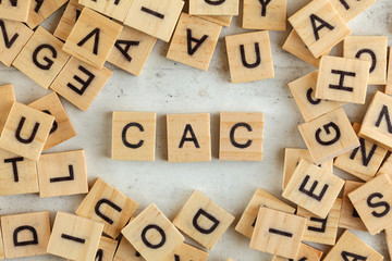 Top down view, pile of square wooden blocks with letters CAC (stands for Customer acquisition cost) on white board.