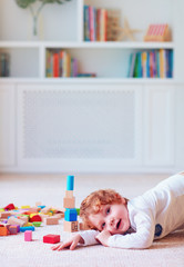 cute toddler baby boy playing with wooden blocks, building a tower at home