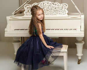 The girl is at the white grand piano.