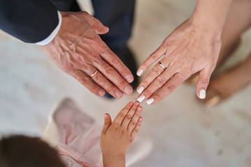 Father, mother and daughter hold hands together