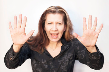 The woman holds her arms in front of her as if protected from someone or something and shouts on a light background