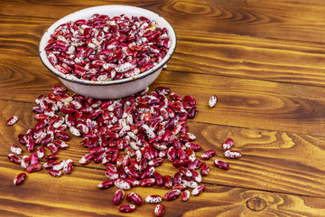 Raw kidney beans in white old enameled bowl on wooden table