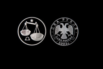Silver coin of the Bank of Russia with the sign of the zodiac Libra on a black isolated background. The coin says: "Two rubles. Bank of Russia".