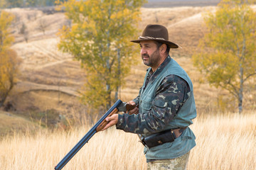 Hunter with a hat and a gun in search of prey in the steppe