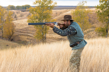 Hunter with a hat and a gun in search of prey in the steppe