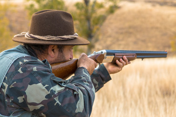 Hunter with a hat and a gun in search of prey in the steppe