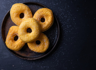 Sweet pieces of sugar doughnuts on dark background , top view