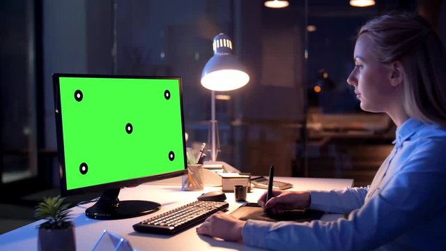 technology, virtual effects and business concept - businesswoman or graphic designer with chroma key green screen on computer monitor and pen tablet working at night office