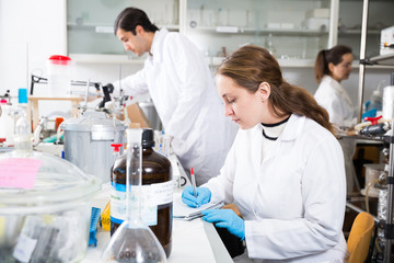 Woman lab technician writing report on chemical experiments