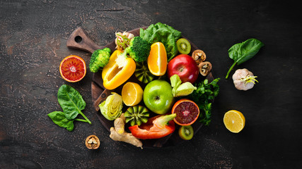 Food containing vitamin C: Orange, lemon, apple, rose, garlic, broccoli, apple, kiwi, spinach. Top view. On a brown background. - obrazy, fototapety, plakaty
