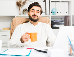 Manager with orange mug working at pc