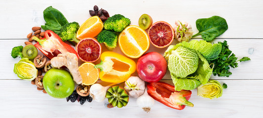 Food containing natural vitamin C: Orange, lemon, apple, rose, garlic, broccoli, apple, kiwi, spinach. Top view. On a white background. - obrazy, fototapety, plakaty