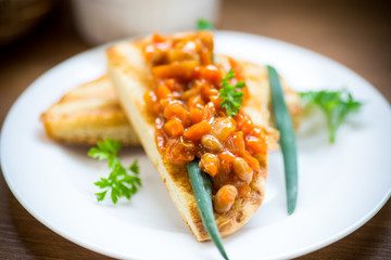 fried bread toasts with stewed beans and vegetables in a plate