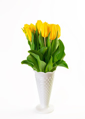 A bouquet of yellow tulips in a white glass vase.