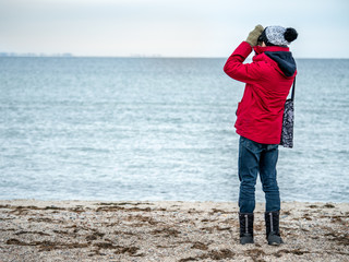 Young man on the beach wachting birds life using telescope