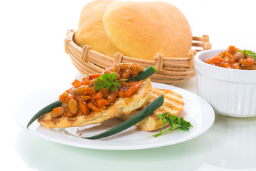 fried bread toasts with stewed beans and vegetables in a plate