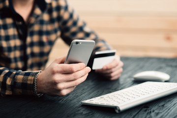 Cropped picture of man with credit card white pattern and phone