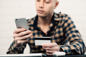 Cropped picture of man with credit card white pattern and phone