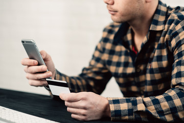 Cropped picture of man with credit card white pattern and phone