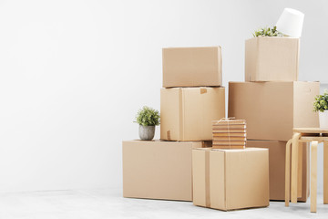 Moving to a new home. Belongings in cardboard boxes, books and green plants in pots stand on the...