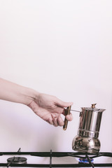 Female hand holds a geyser coffee maker on a gas stove. Making coffee at home
