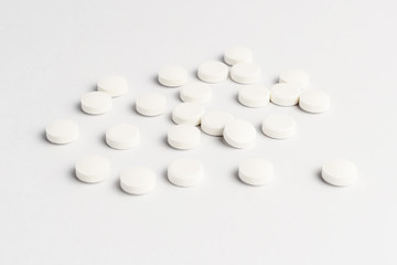 Side view of a group of white pills on white background, in random order