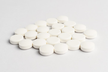 Side view of a group of white pills on white background, in random order