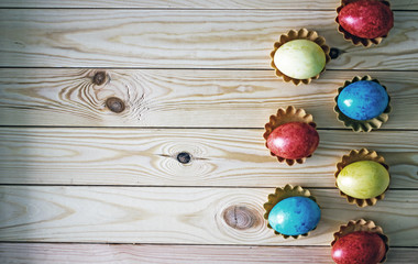 Easter eggs of different colors of yellow red and blue stand in two rows in a checkerboard pattern on a wooden table. Easter background, there is a place for an inscription.