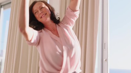 happy woman dancing in hotel room having fun enjoying successful travel vacation healthy middle aged female celebrating retirement at sunrise