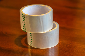 Transparent adhesive tape roll on wooden background