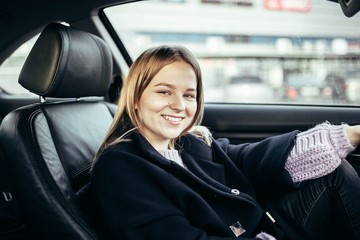 Beautiful young girl driver driving a car with leather seats.