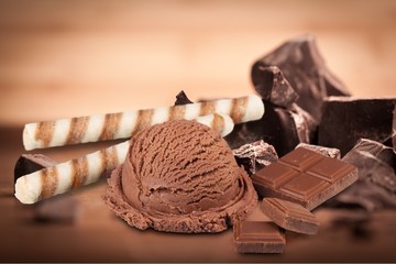 Broken chocolate bar and ice cream scoop on background