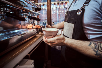 Barista holding a cup with an aromatic cappuccino in a cafe or restaurant 