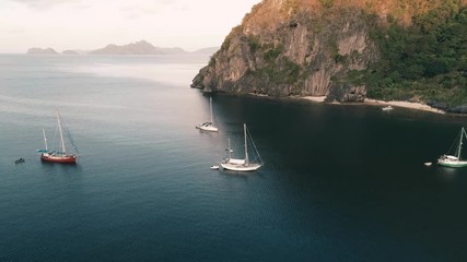 Aerial drone shot of high mountain covered with tropical forest and boats anchored in the bay. Tropical landscape. Travel concept Philippines,El Nido.