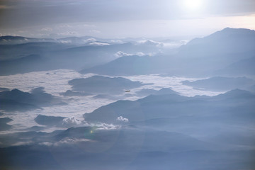 Fototapeta na wymiar View from plane window to another plane flying over clouds and mountains