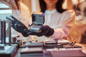 Woman assistant shows the exclusive gold ring in the luxury jewelry store