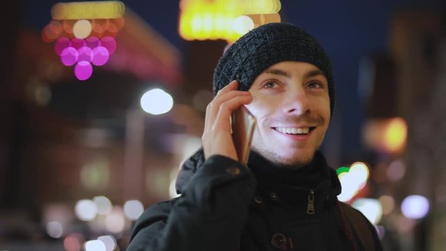 Man answers on the incoming call in the night city street, slowmotion