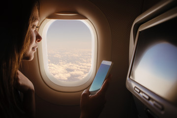 Fototapeta na wymiar Woman in airplane using mobile phone